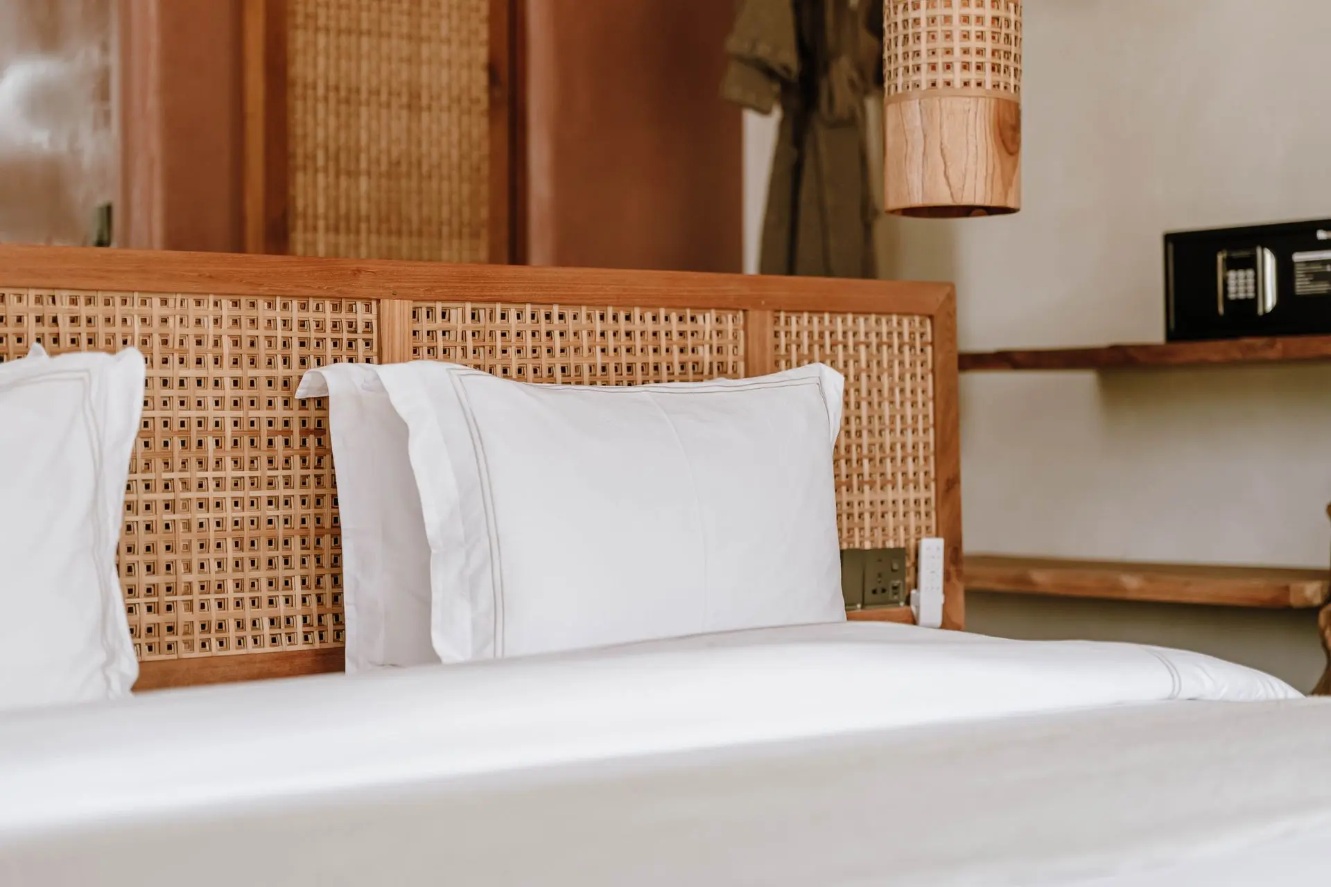 Đầu giường đan mây, gối và ga trắng trong phòng ngủ ấm