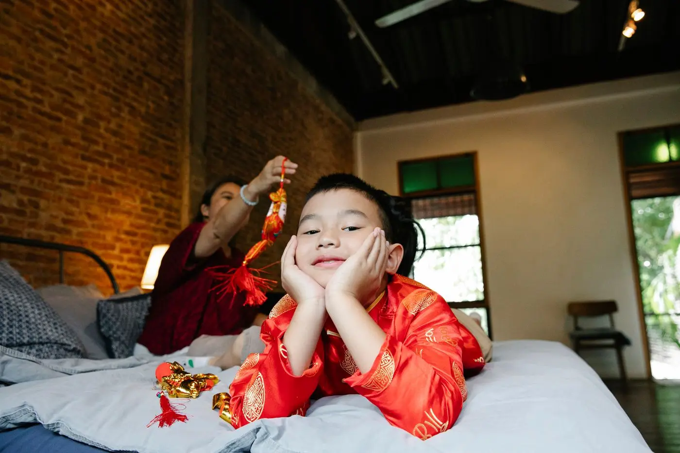 Hai mẹ con chơi đùa trên chiếc giường trải ga trắng