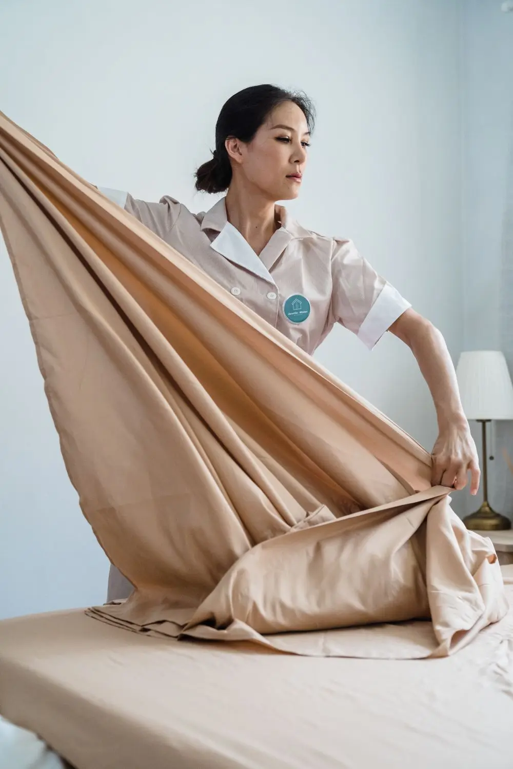 Người phụ nữ trải tấm ga màu be lên nệm
